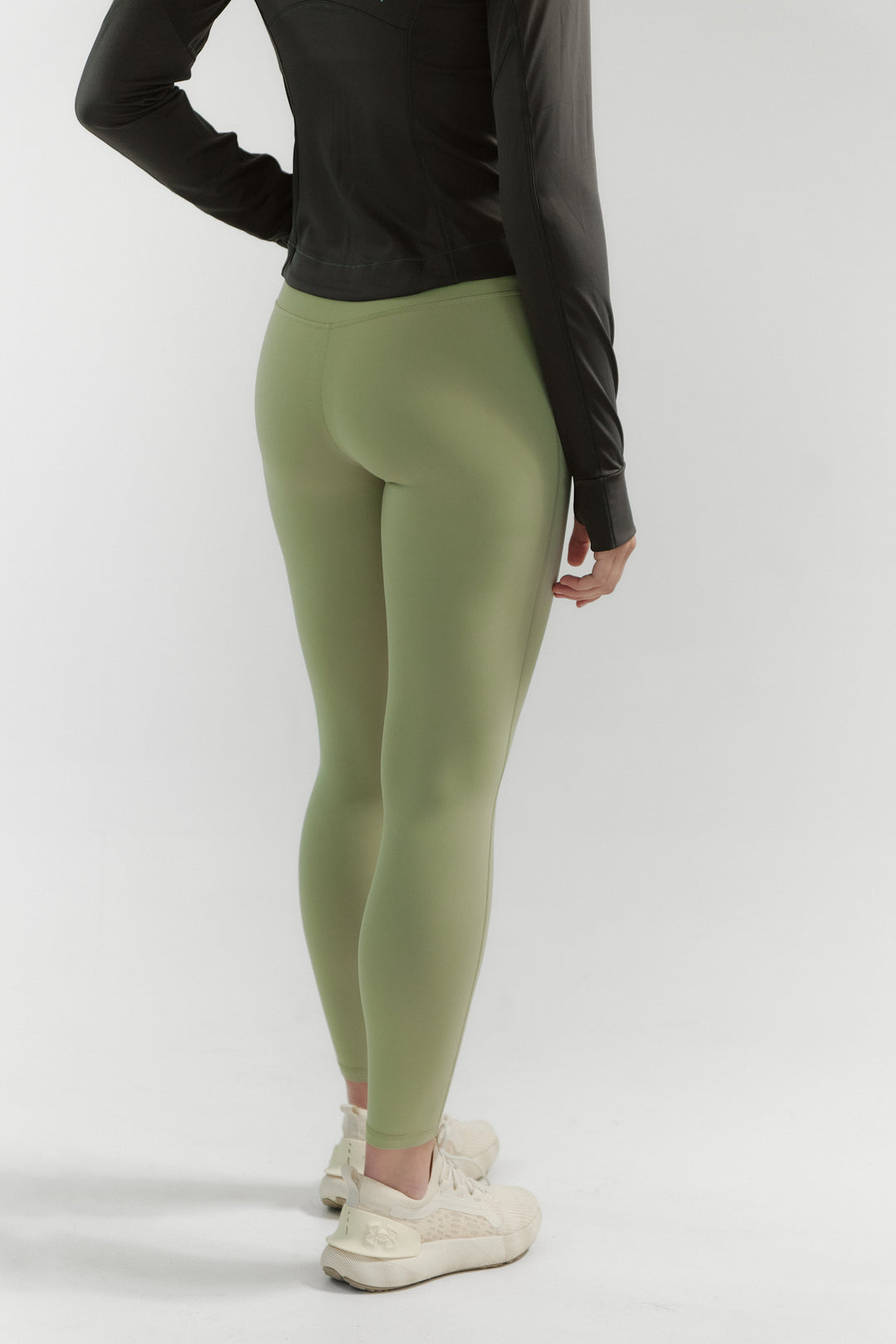 Person wearing green leggings and a black top on a white background