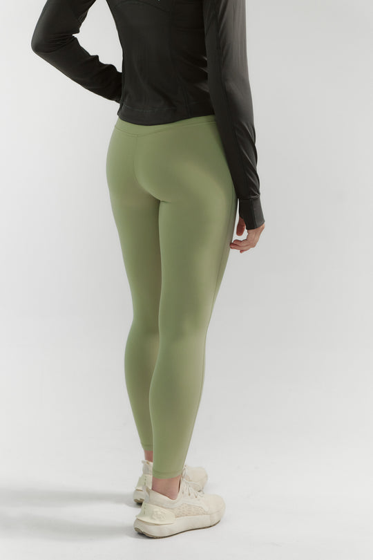 Person wearing green leggings and a black top on a white background