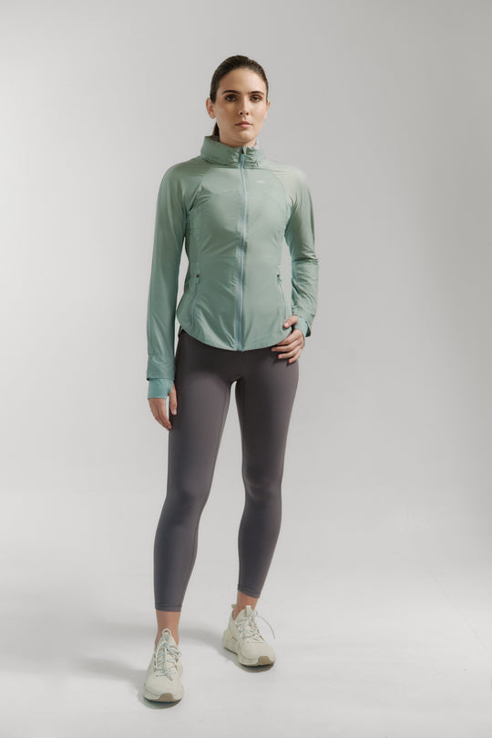 Woman wearing a green jacket and gray leggings on a white background