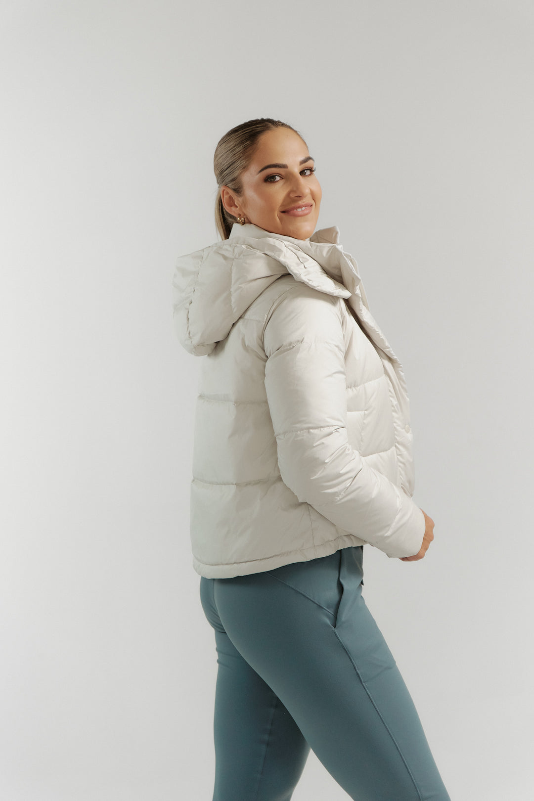 Woman wearing a white puffer jacket against a light gray background