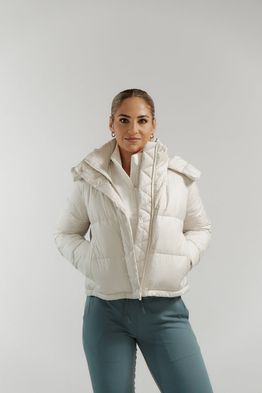 Person wearing a white puffer jacket on a plain background