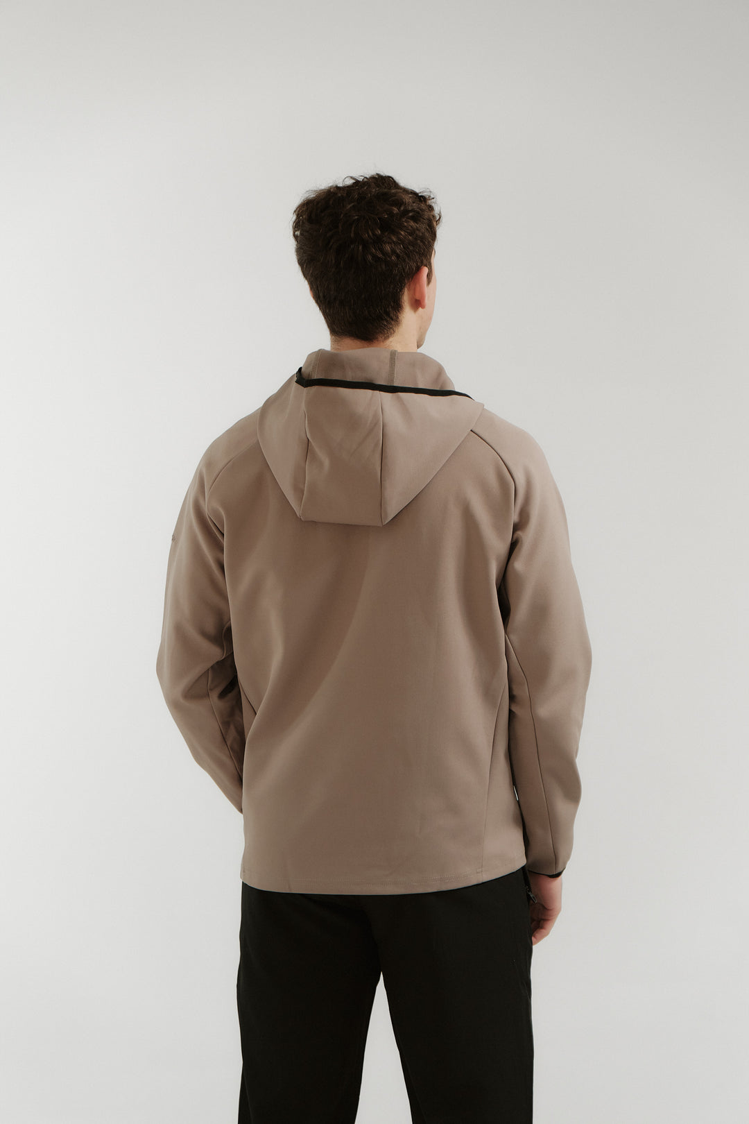 Person wearing a beige jacket with a hood on a white background